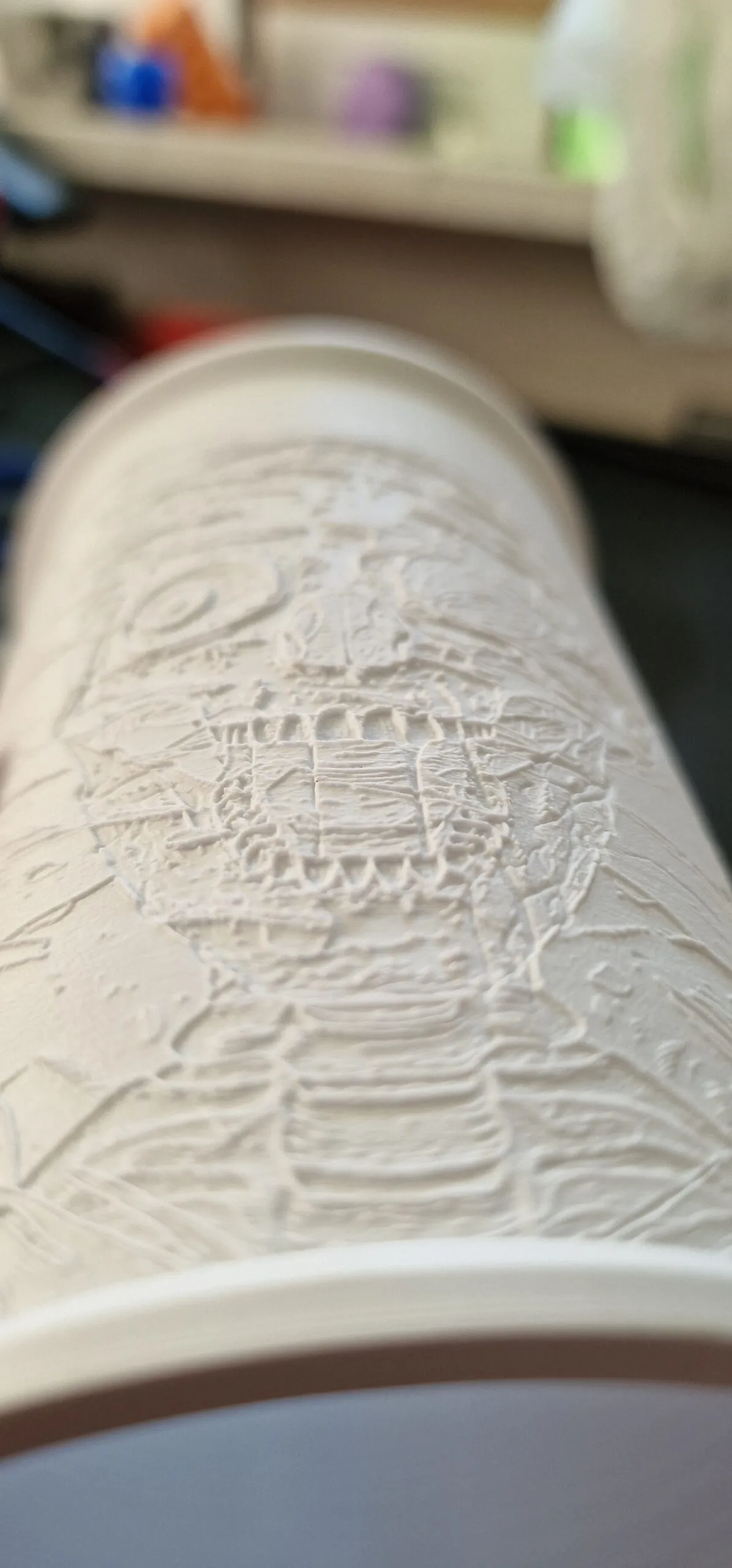 Weißer Zylinder mit eingedrucktem Relief, in der Hand gehalten, ohne Beleuchtung